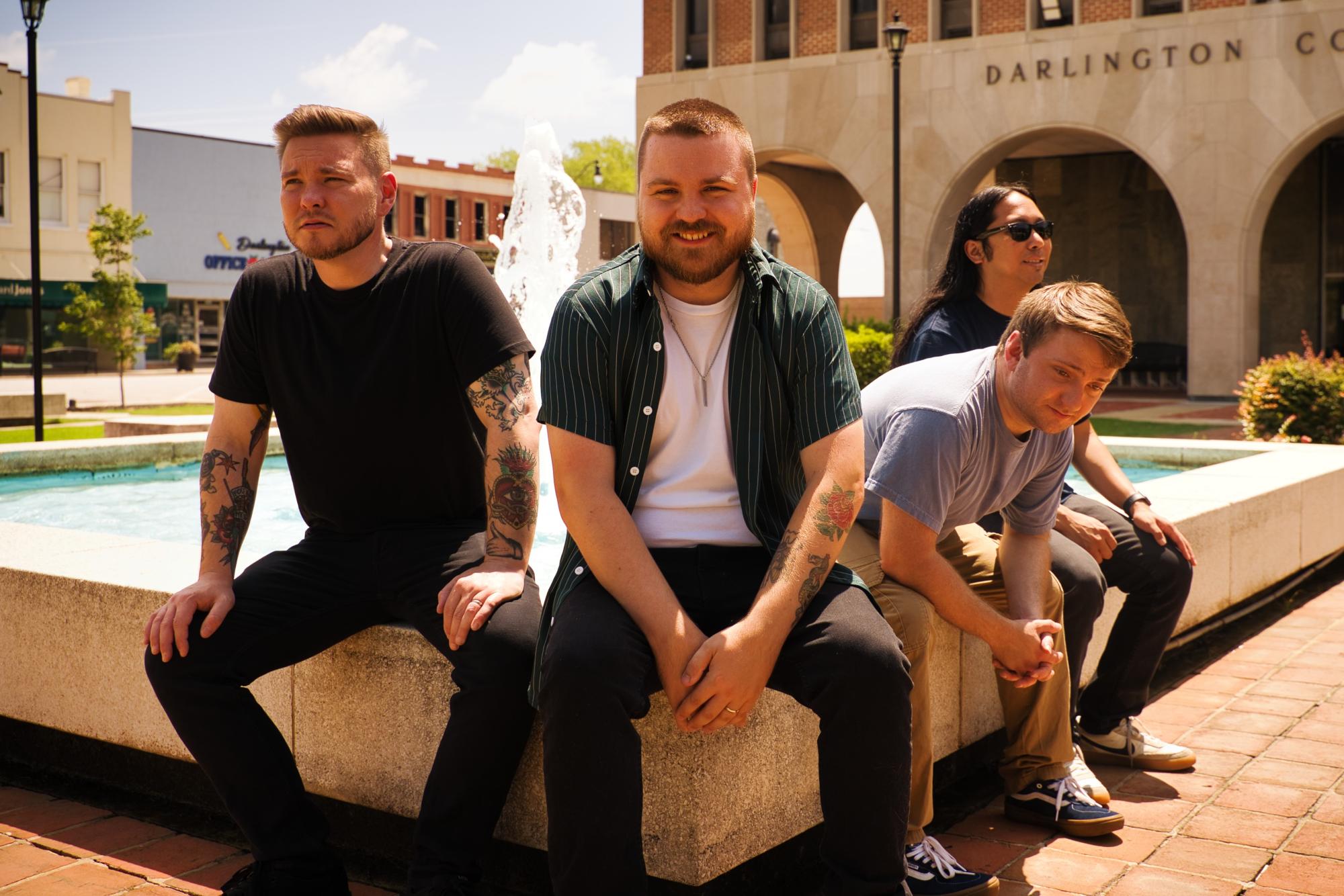 four young men sitting next to a fountain in Darlington, SC's Courthouse Square