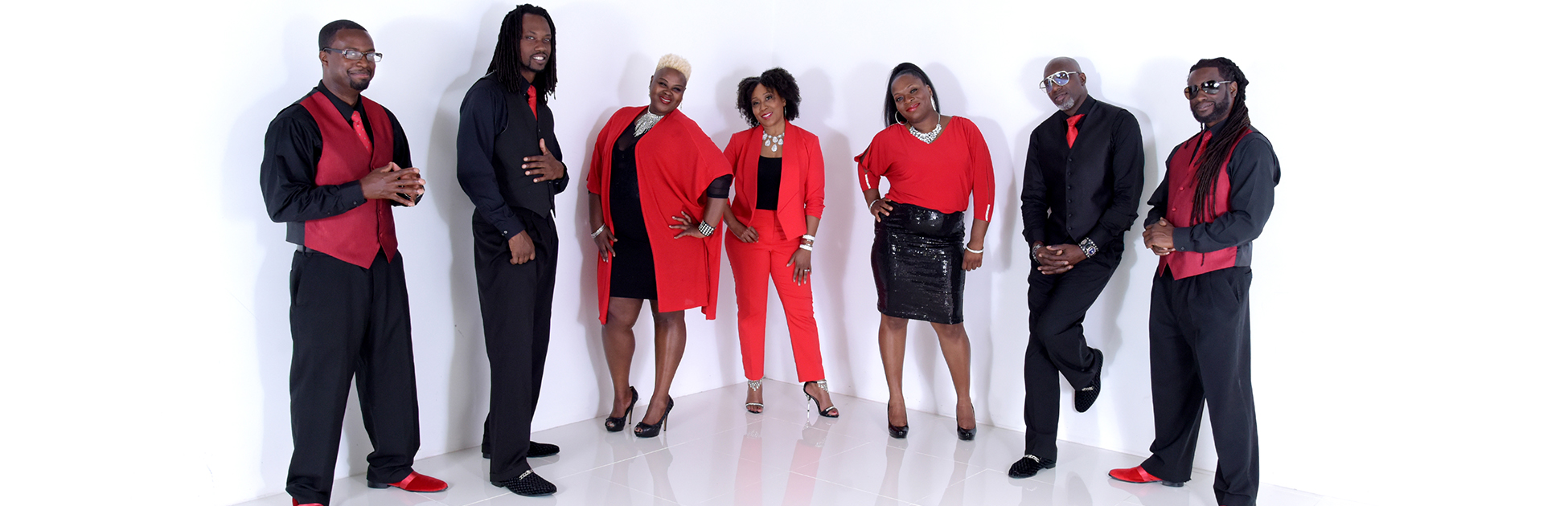 A seven-piece group, Tru Sol Band, wearing black and red against a white backdrop.